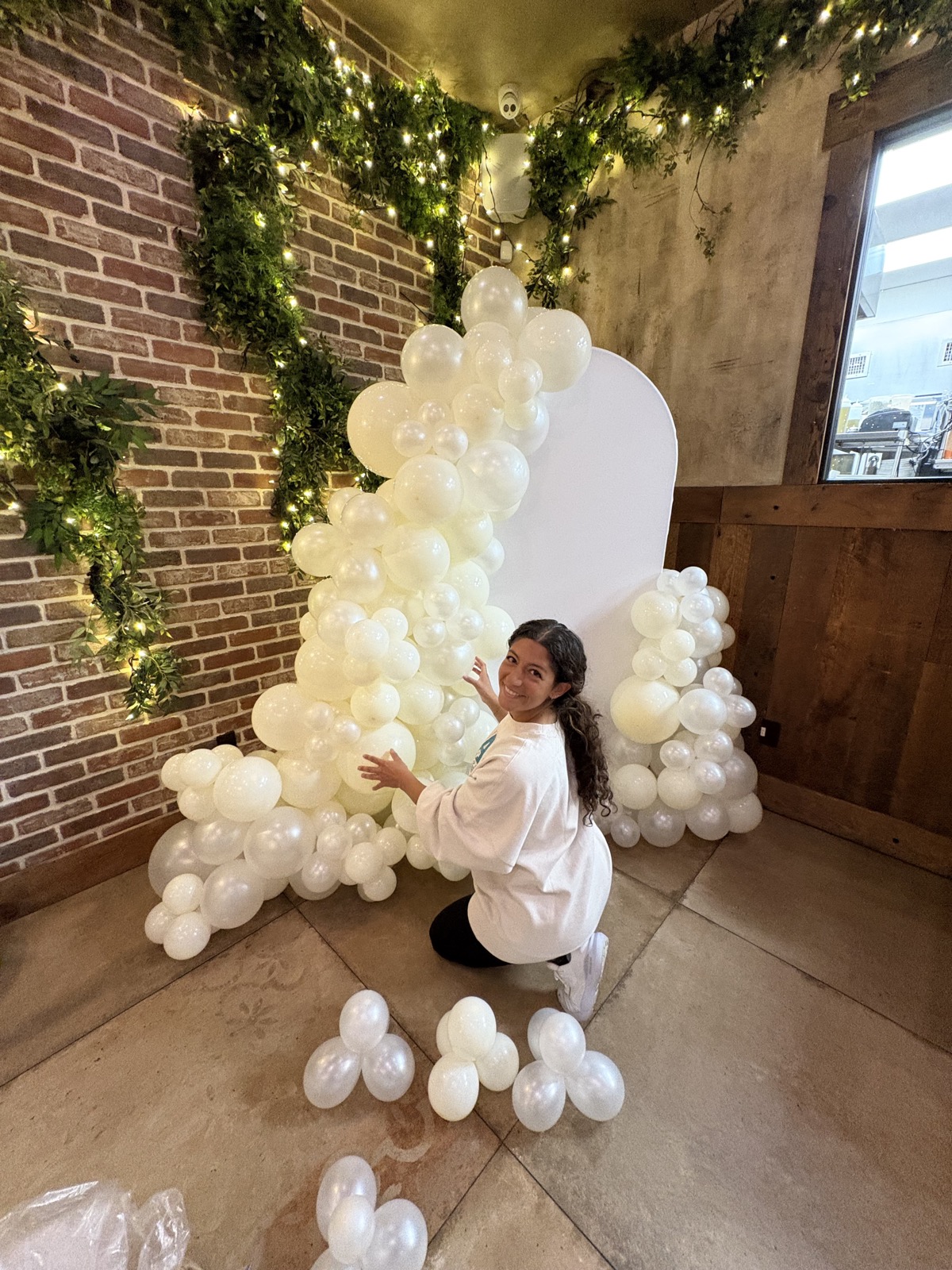 Lisa assembling a white organic balloon arch in Northern NJ